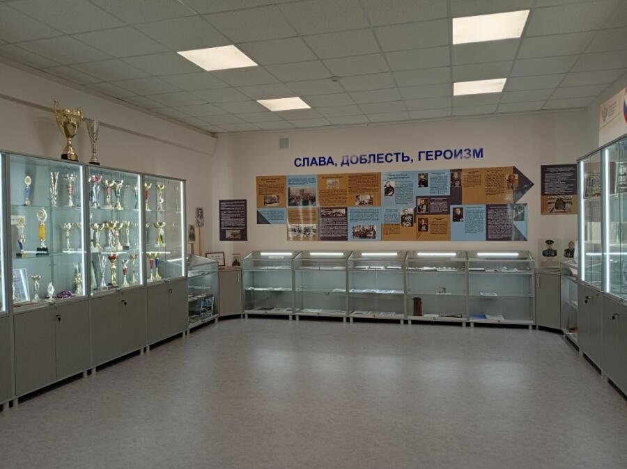 The same room as the school history museum: lit display cases, trophies and a wall of panels on the school's history
