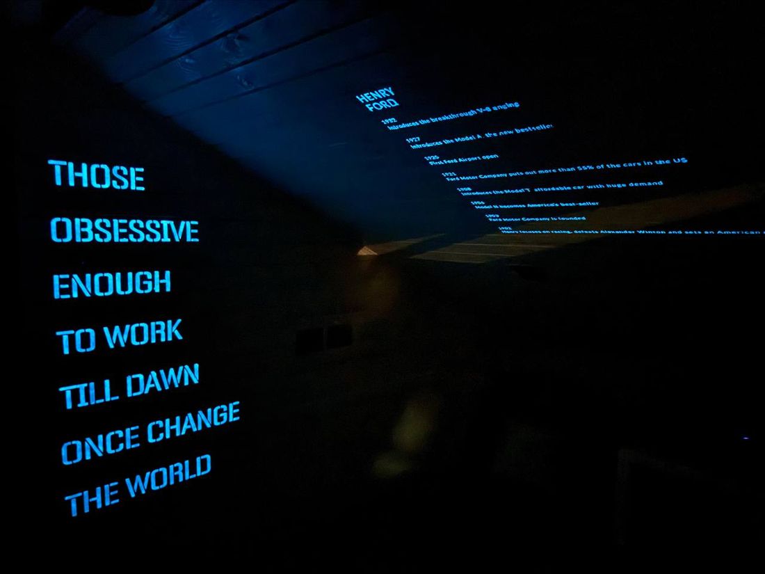 The stencilled line glowing blue next to a Henry Ford timeline on the ceiling