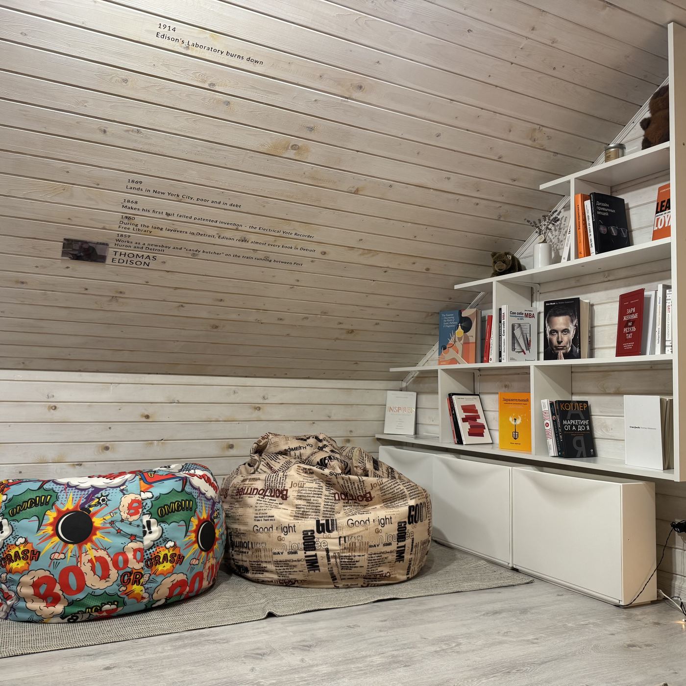 The finished reading corner: bean bags, white bookshelves and a Thomas Edison timeline on the slope