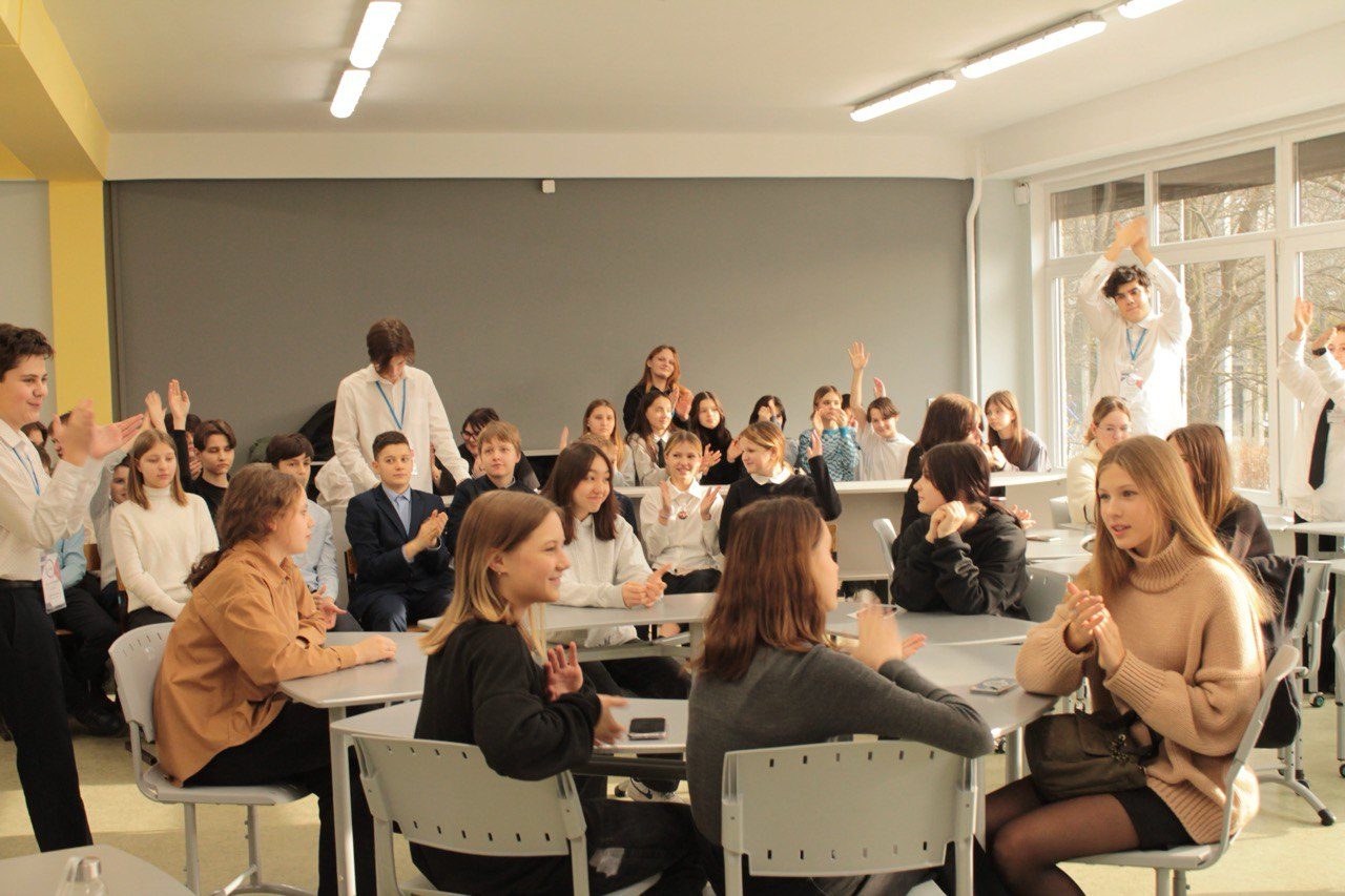 Students applauding at an open meeting with a student of the joint HSE and NES programme