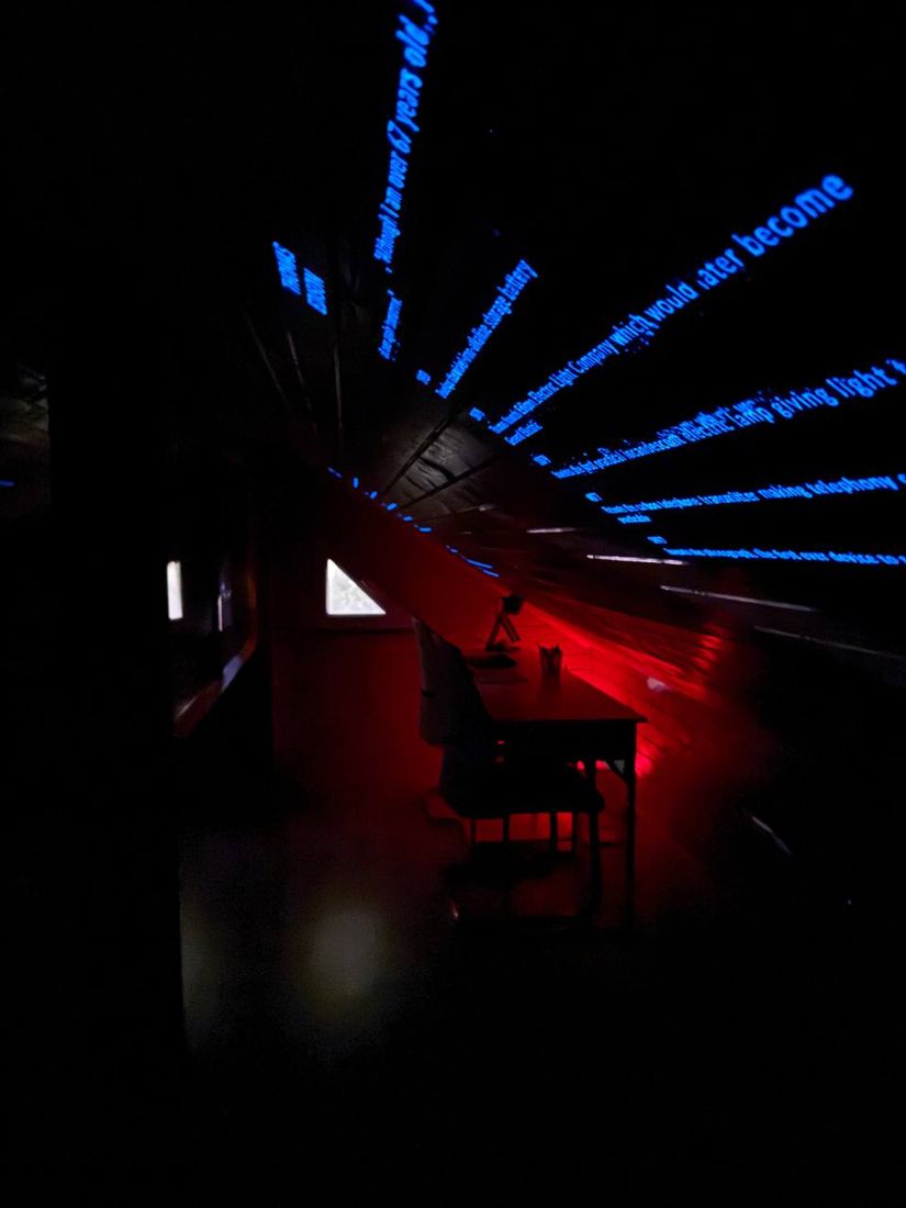 The work desk lit red, with blue timelines projected across the sloped ceiling